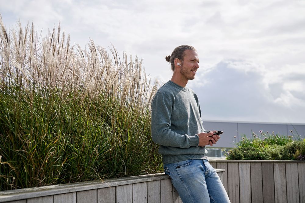 Mandlig medarbejder i samtale over telefonen på arbejdspladsens udendørs terrasse.