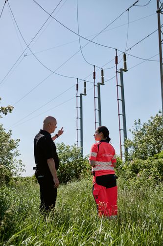 En kvindelig tekniker og en mandlig projektleder gennemgår et projekt på stedet.